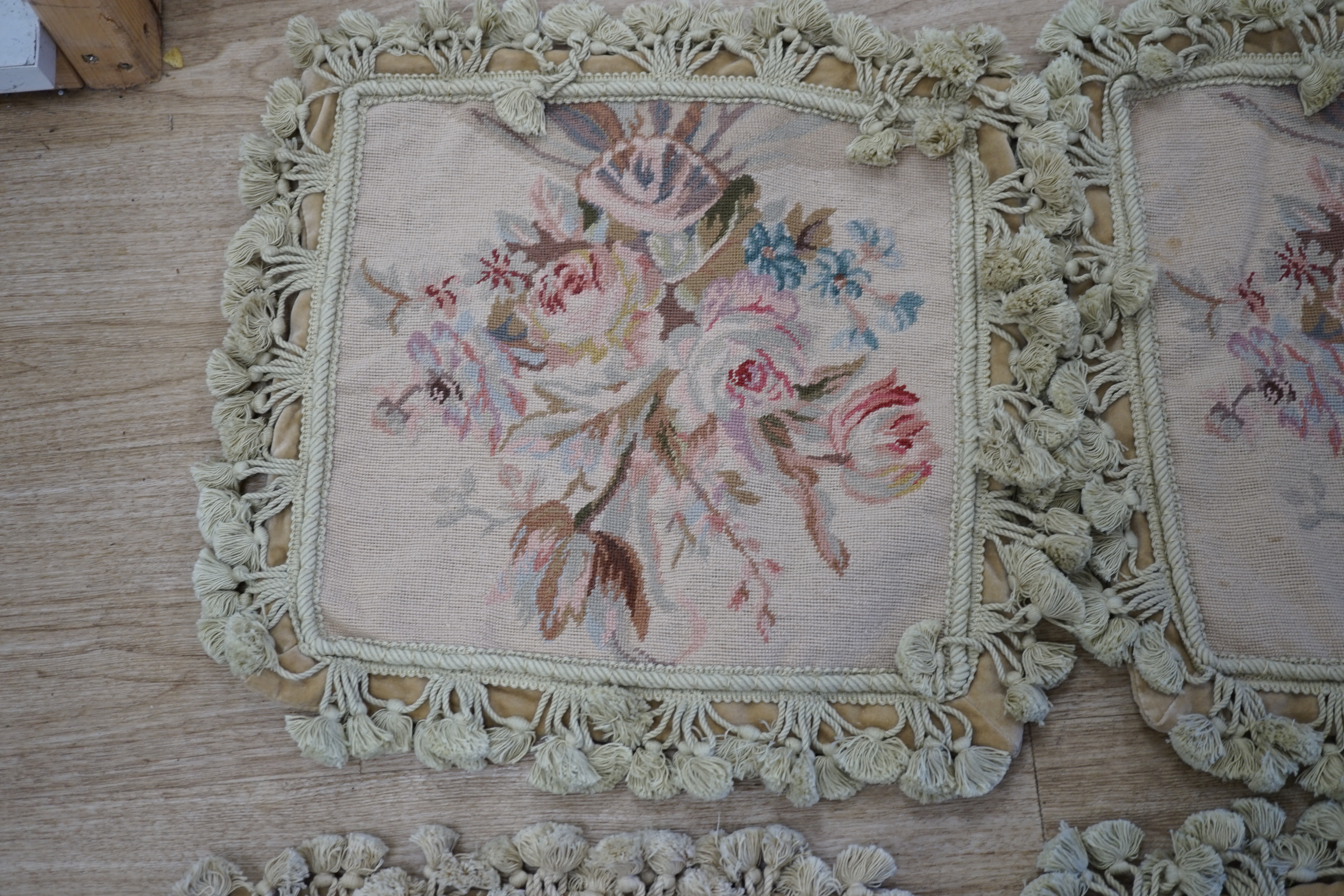 Three small square rose designed wool worked cushion covers and one similar larger cushion cover all with cotton tasselled edging, smaller covers 38cm square, larger cover 38cm x 48cm. Condition - good